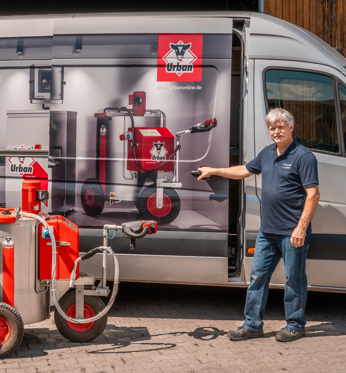 Stefan Lindner am Servicefahrzeug mit Urban-Kälbertränketechnik und einem fahrbaren Milchtaxi